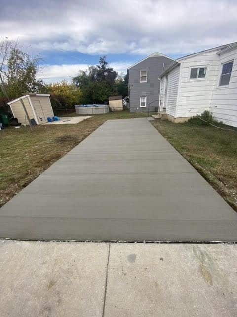 Freshly poured concrete pathway in a backyard surrounded by grass