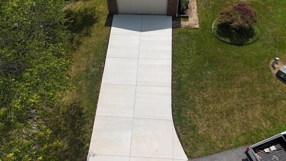 Aerial view of a concrete driveway leading to a garage surrounded by grass