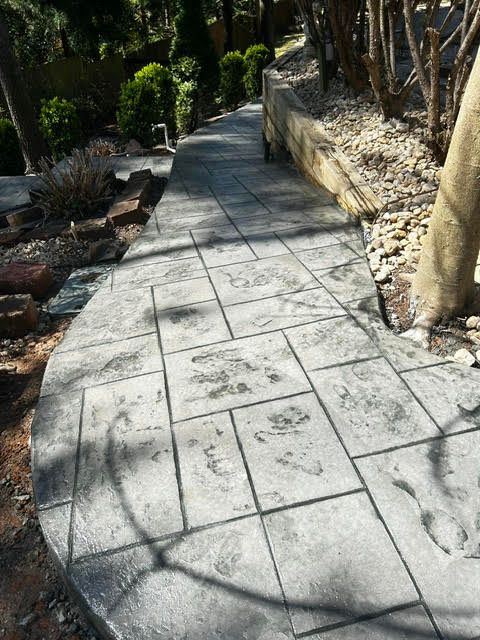 Concrete pathway with textured square patterns winding through a garden.