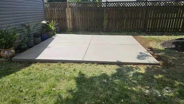 Concrete patio in a Maryland backyard with a wooden fence and lawn