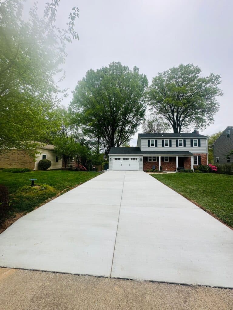 Long concrete driveway leading to a two story house with a white garage door