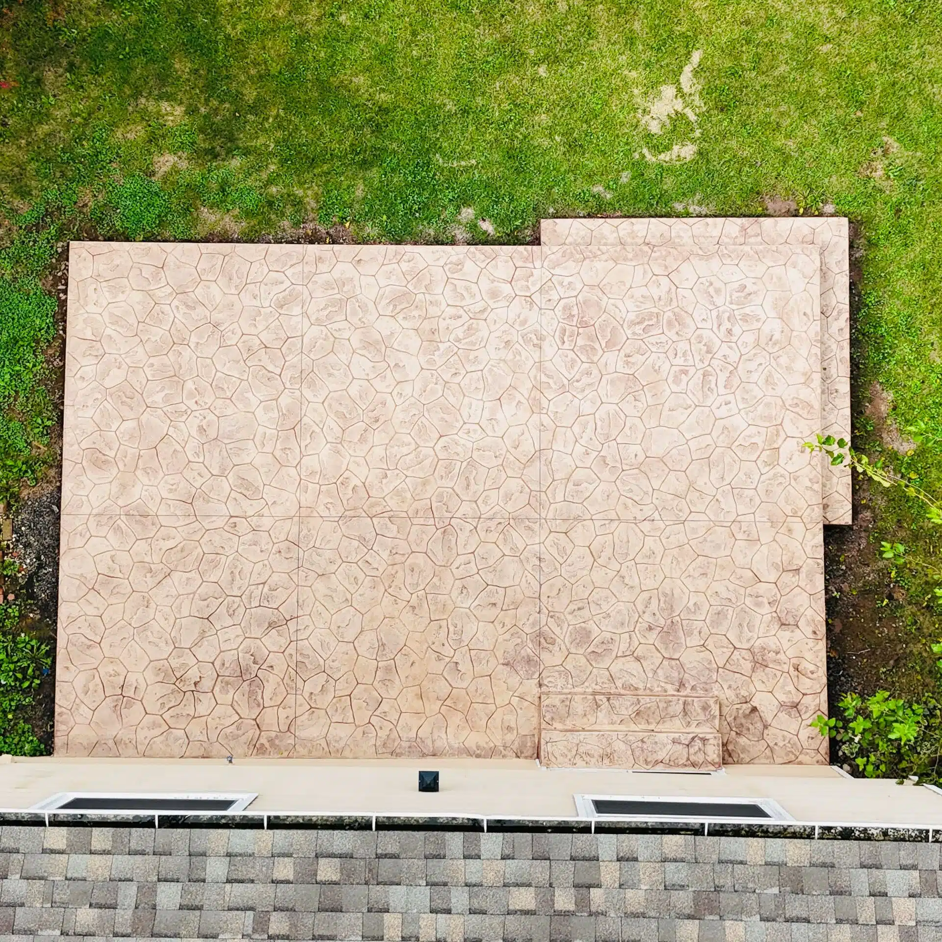Overhead view of a finished concrete patio next to a grassy lawn