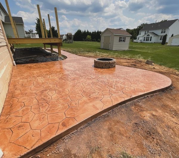 Stamped concrete patio with a fire pit next to a Maryland house and deck
